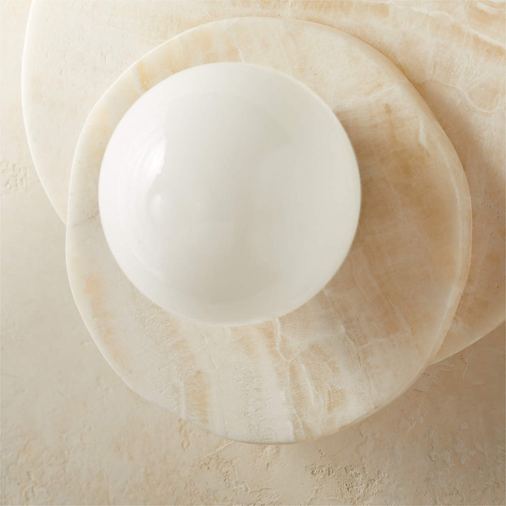 A close crop of the Clérachic wall light reveals the natural veining across its stacked alabaster discs behind the glass globe.