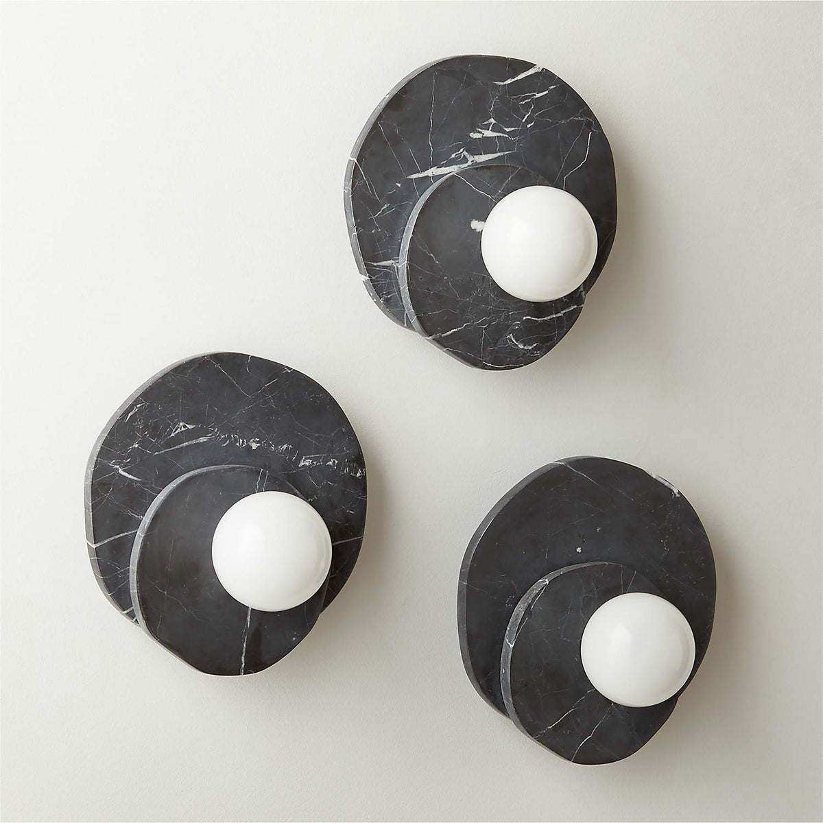 Three Clérachic wall lights in black marble, sized small to large, are grouped together to show the range side by side.