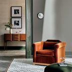 Above a wood sideboard beside an orange velvet armchair, a single Clérachic wall light adds a warm accent to the room.