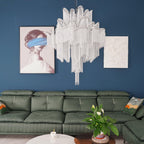 Against a dark blue wall, this lit silver Clérachic chandelier hangs beside framed art and a green leather sofa.