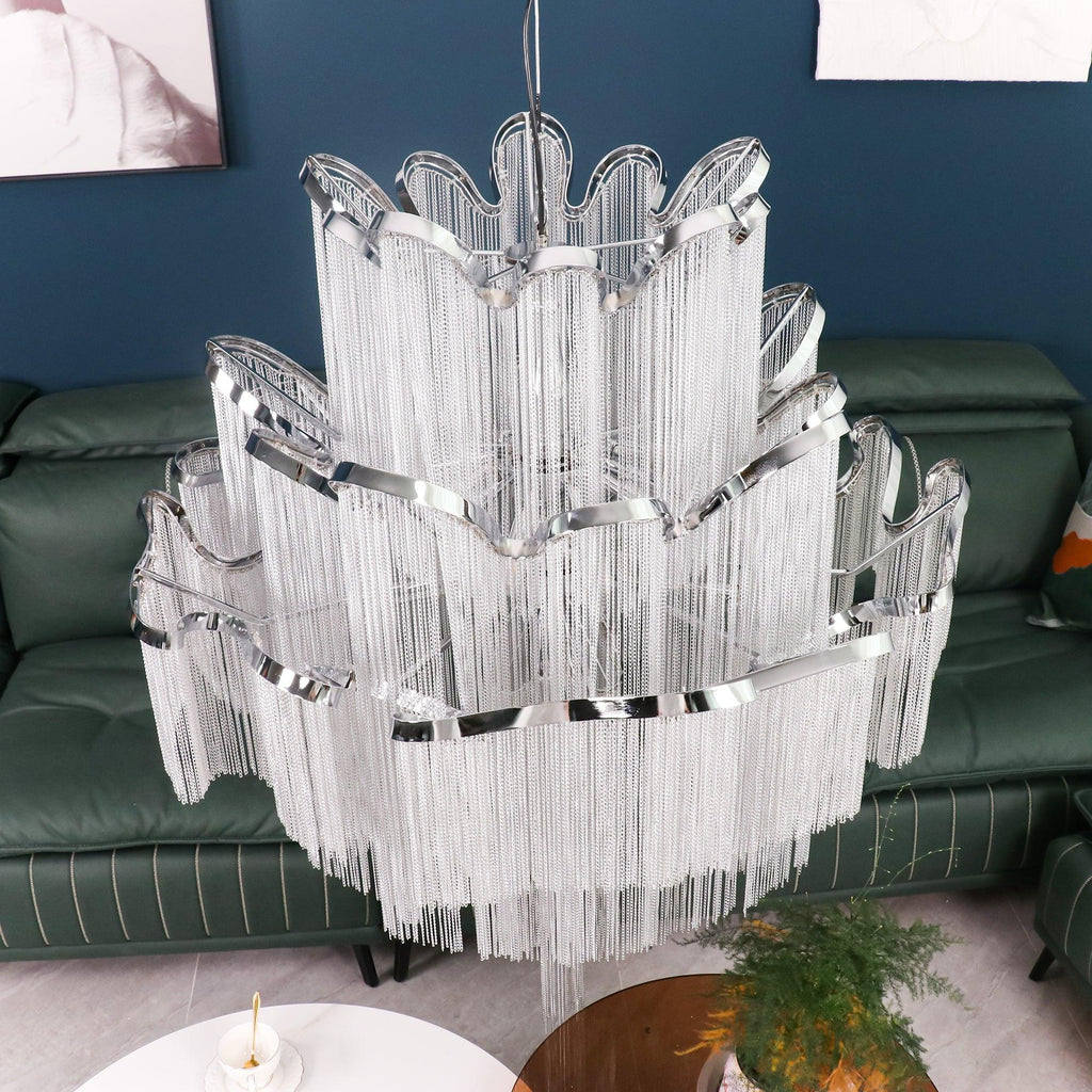 Close beside a green leather sofa, this lit silver Clérachic chandelier shows its full tiered scale.