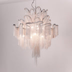 On a soft pink-grey backdrop, this lit silver Clérachic chandelier is shown with its chain tiers glowing.