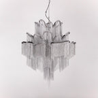 Unlit against a white backdrop, this silver Clérachic chandelier's chain fringe hangs in full view.