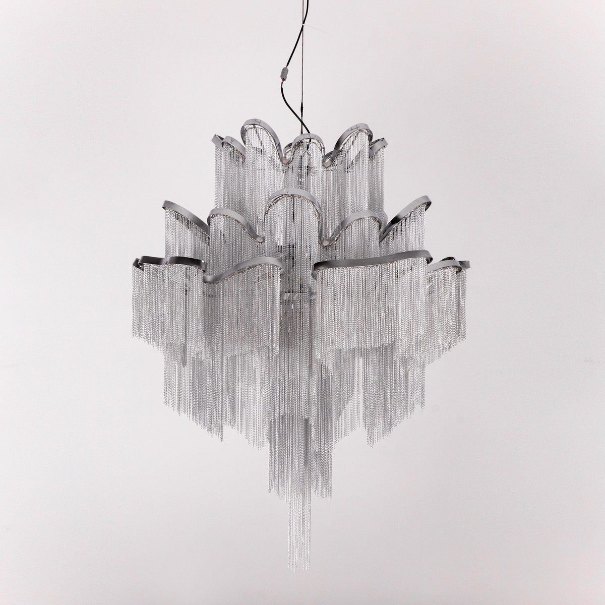 Unlit against a white backdrop, this silver Clérachic chandelier's chain fringe hangs in full view.