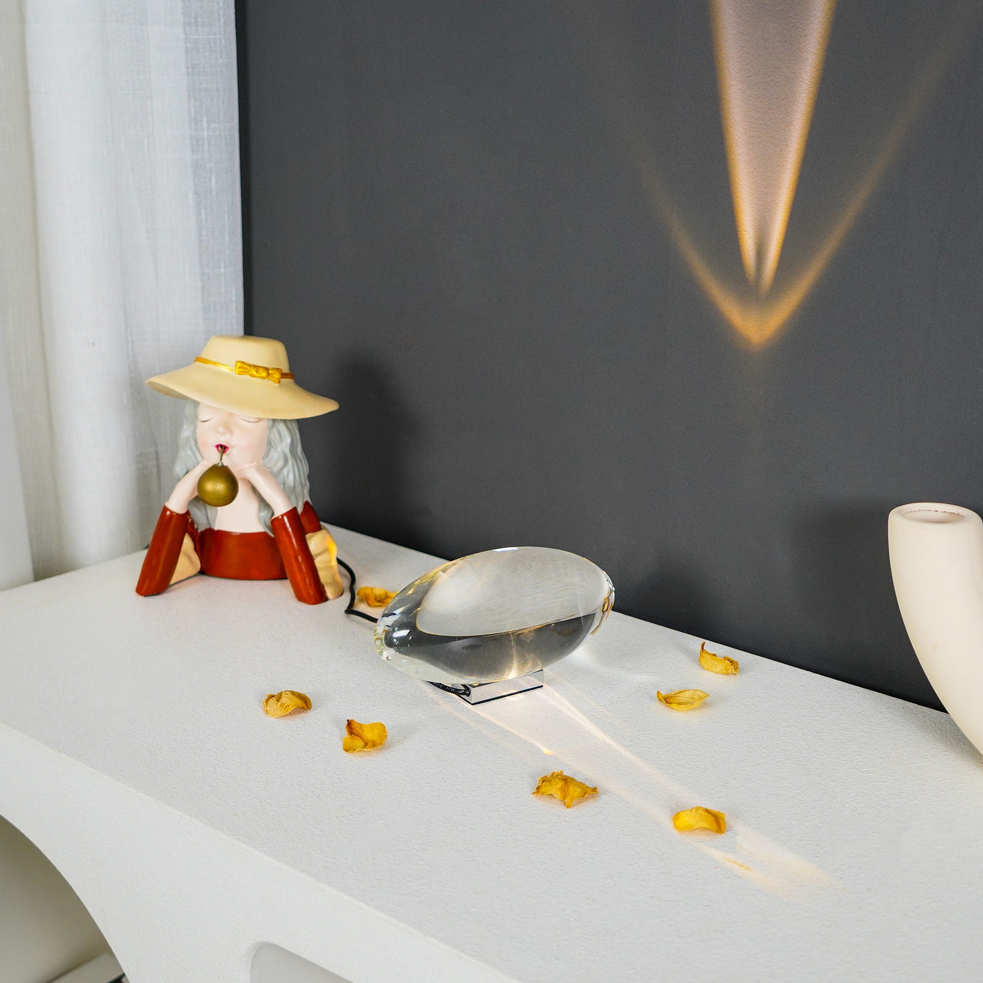 Clear crystal oval table lamp lit warmly on a bedside table