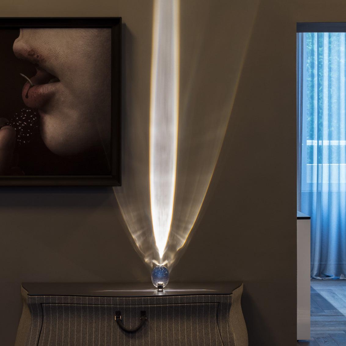 Oval crystal table lamp casting a warm intimate glow on a shelf