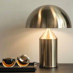 Sculptural metal table lamp lit on a bedside surface