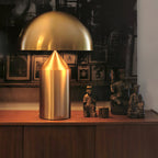 Sculptural metal table lamp glowing beside seating