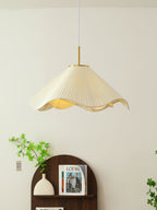 A trailing green vine climbs beside this beige Clérachic pendant light above a dark wood console.