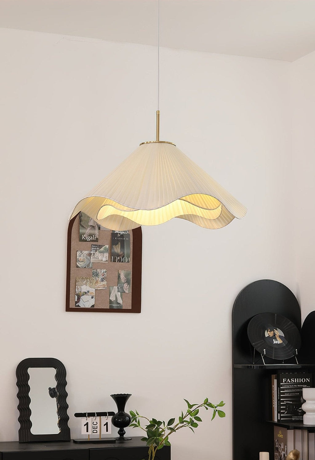 A round black mirror and framed photos hang beside this beige Clérachic pendant light.