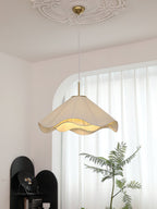 Beneath an ornate ceiling medallion, this beige Clérachic pendant light glows in front of a sheer curtain.