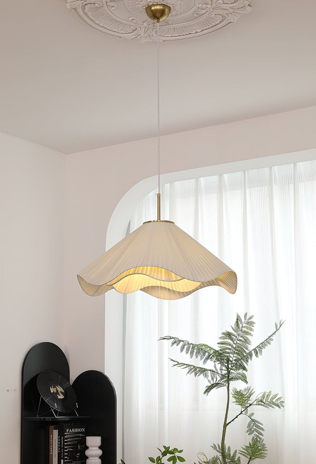 Beneath an arched window, this beige Clérachic pendant light hangs with a leafy plant reaching up beside it.