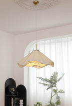 Beneath an arched window, this beige Clérachic pendant light hangs with a leafy plant reaching up beside it.