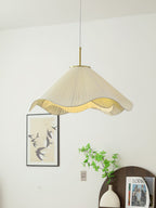 Above a dark console holding a magazine, this beige Clérachic pendant light glows near a framed bird print.