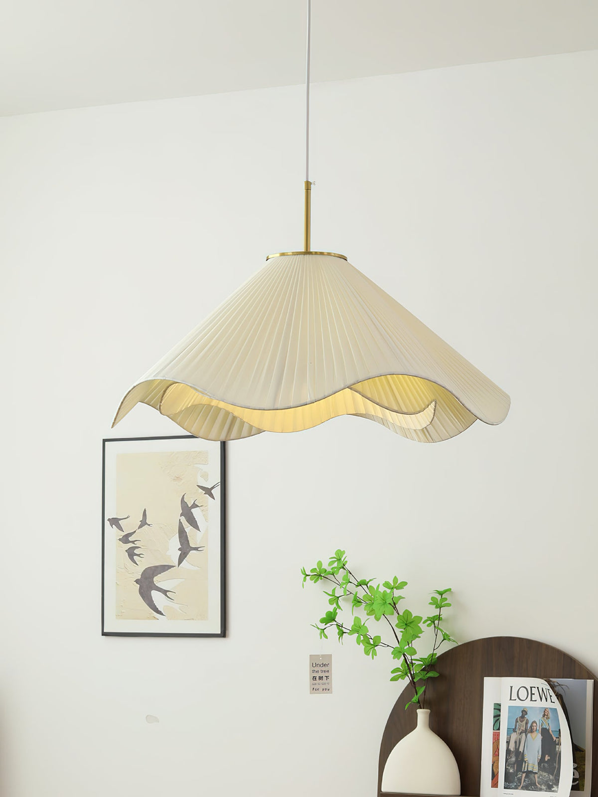 Above a dark console holding a magazine, this beige Clérachic pendant light glows near a framed bird print.