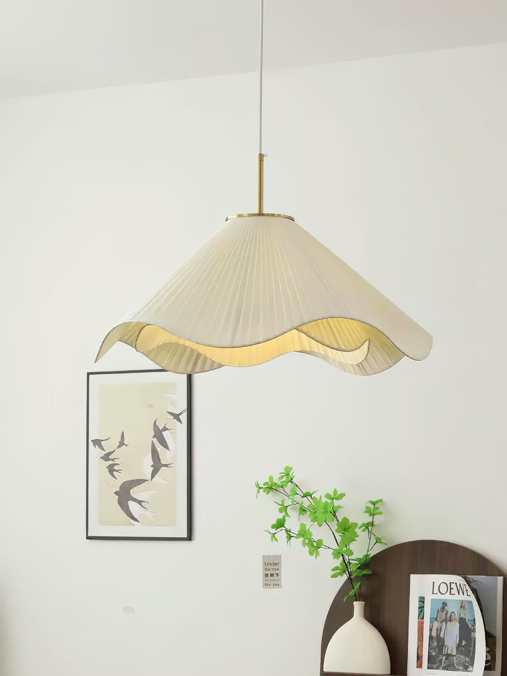 Near a framed bird print, this beige Clérachic pendant light glows above a black console holding a small vase.