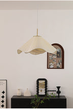 Above a dark console set with a small mirror and ceramic vases, this beige Clérachic pendant light glows warmly.