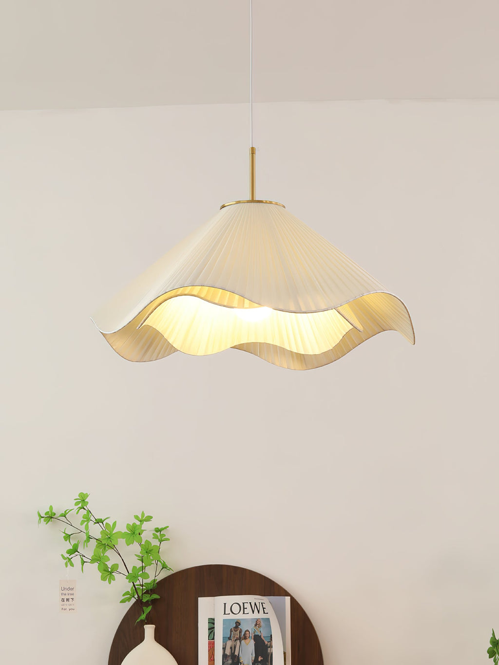 In a sparsely styled corner, this beige Clérachic pendant light hangs beside a trailing plant.