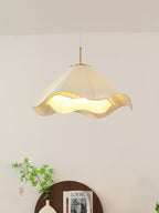 In a sparsely styled corner, this beige Clérachic pendant light hangs beside a trailing plant.