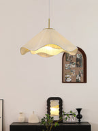 Beside a wall-mounted photo display, this beige Clérachic pendant light hangs above a dark wood console.