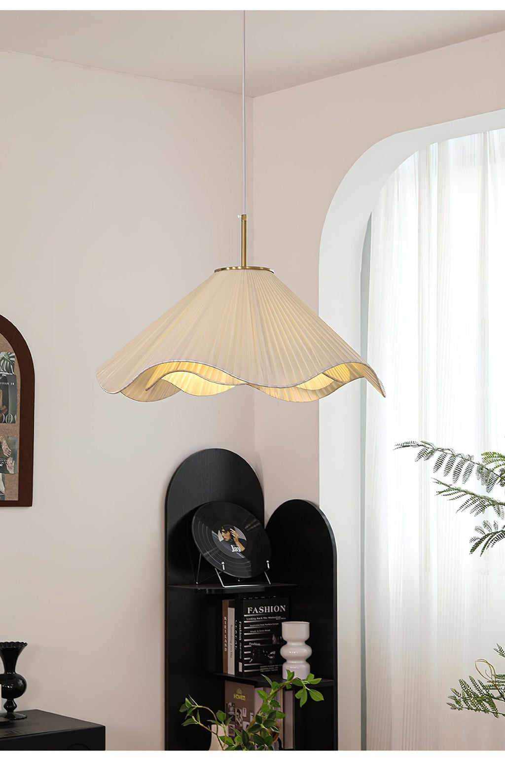 Near a black shelving unit topped with a trailing plant, this beige Clérachic pendant light hangs softly lit.