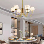Clérachic lit above a round marble dining table laid for a meal in an open-plan apartment