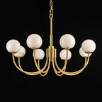 Clérachic lit on a black backdrop with a long chain drop, brass arms curving out beneath the globes