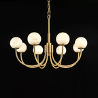 Clérachic lit on black in a wider frame, the warm globes contrasting with the polished brass arms