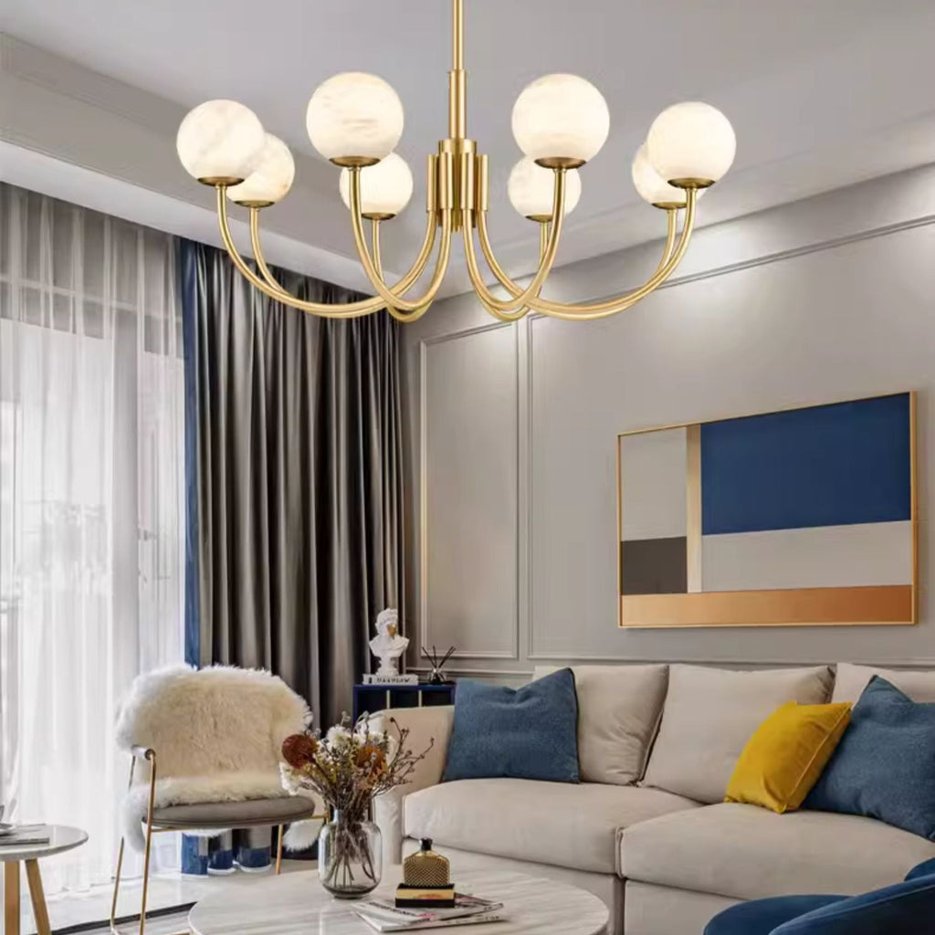 The Clérachic chandelier lit above a pale sectional with blue and mustard cushions in a bright living room