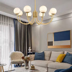 The Clérachic chandelier lit above a pale sectional with blue and mustard cushions in a bright living room