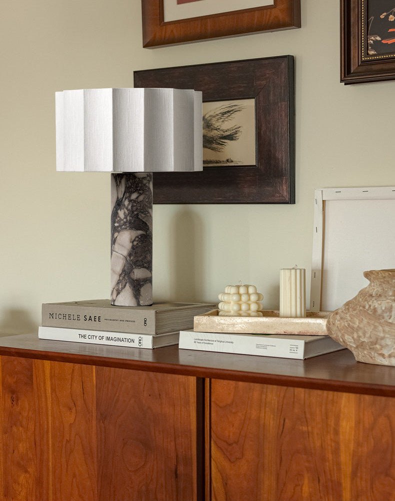 The Clérachic table lamp sits on a wooden sideboard styled with stacked books, candles and a small ceramic vase.