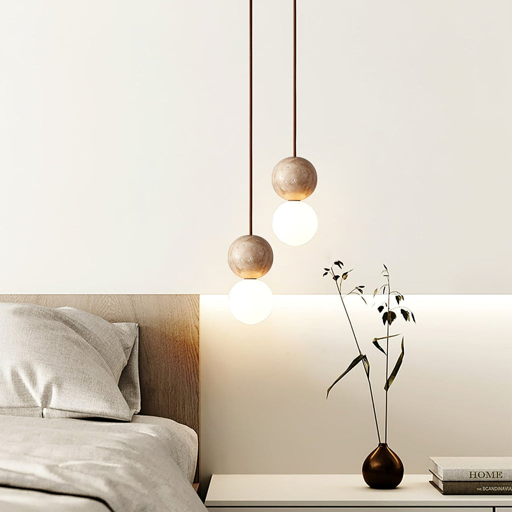 This two-tier Clérachic pendant lights a bedside table holding a dark vase of dried branches.