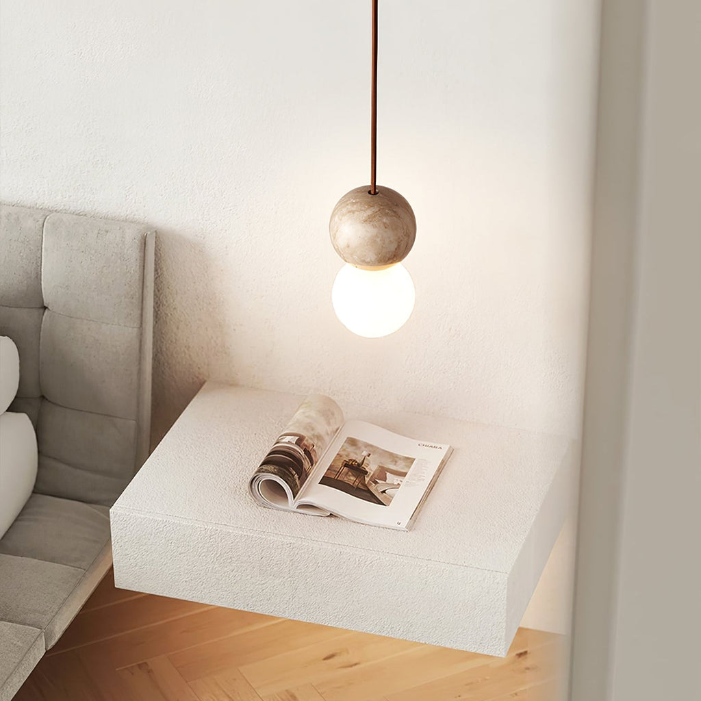A Clérachic pendant hangs beside a magazine on a floating white stone side table.