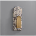 Clérachic marble arch wall sconce photographed unlit on a plain grey studio wall, showing the arched stone shape and brass panel.