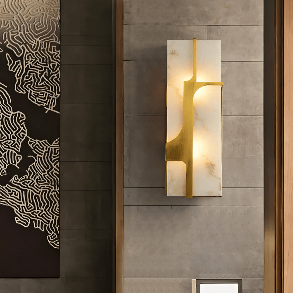 Closer square view of the lit Aurevon sconce on the same stone wall, brass bracket in detail