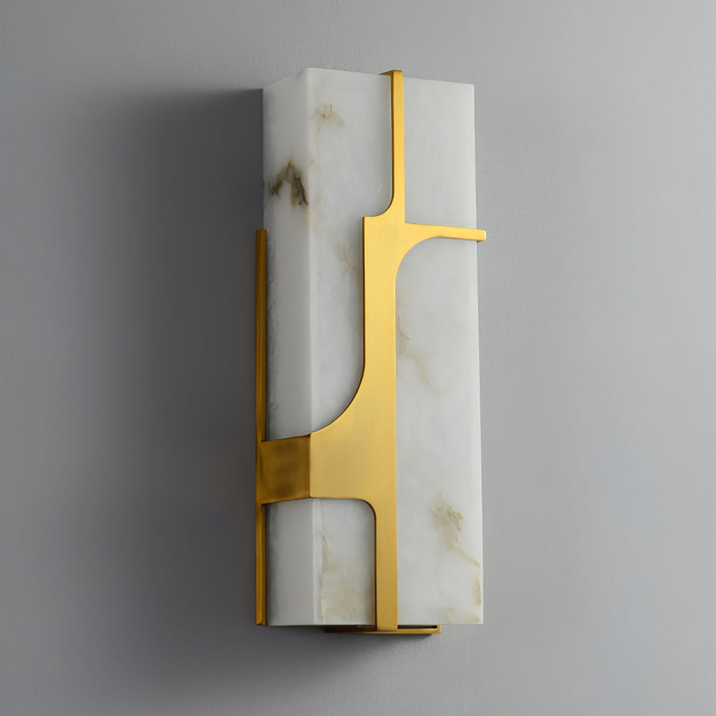 Aurevon alabaster wall sconce seen at an angle, unlit, its brushed brass bracket against pale stone