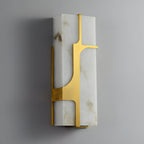 Aurevon alabaster wall sconce seen at an angle, unlit, its brushed brass bracket against pale stone