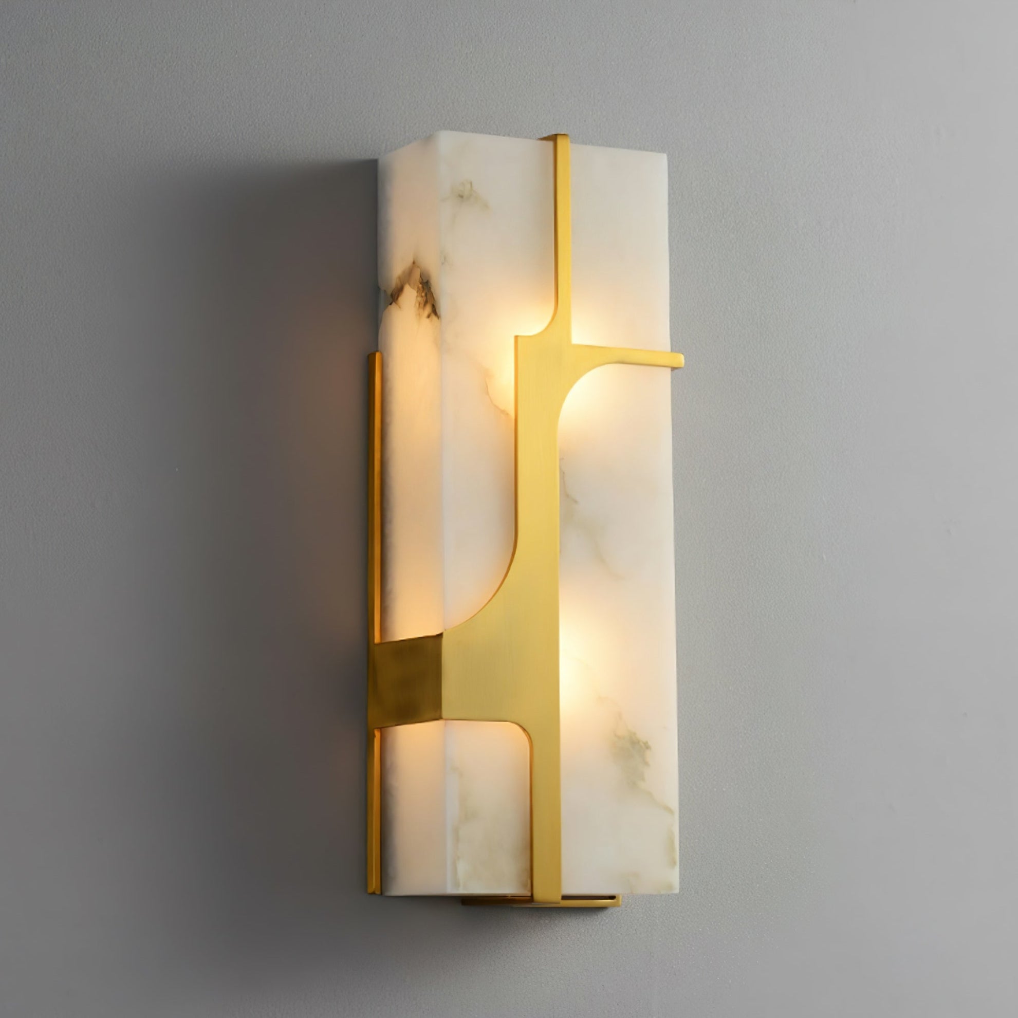 The Aurevon sconce lit, warm light spilling through the alabaster around its brass bracket