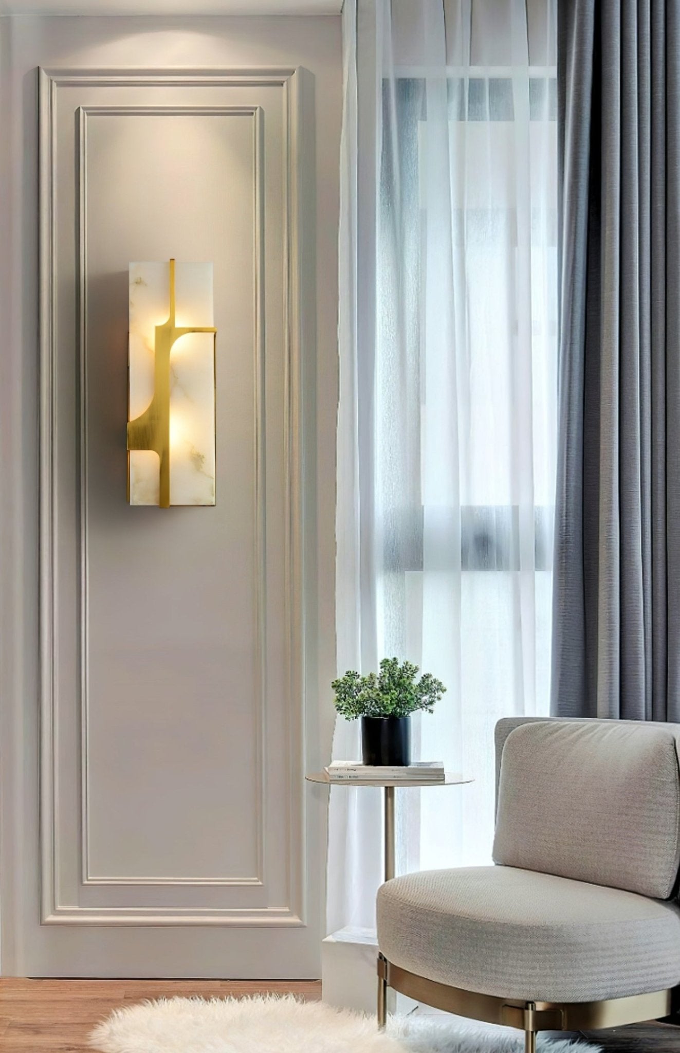 Aurevon sconce lit on a panelled wall beside a sheer-curtained window and a round grey chair