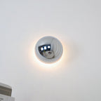 Polished sphere wall sconce with warm light on a wall