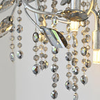 Close-up of the leaf-shaped crystals and faceted bead strands, with a bulb lit behind.
