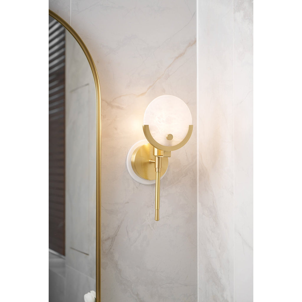 Clérachic zavarara sconce lit at an angle on marble tile, the arched brass mirror edge in the foreground.