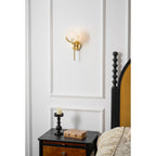 Clérachic closer bedroom crop of the Zavarara sconce lit on white panelling above an antique nightstand.