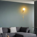 Clérachic zavarara sconce lit above a dark grey sectional, casting a warm halo across a deep teal living room wall.