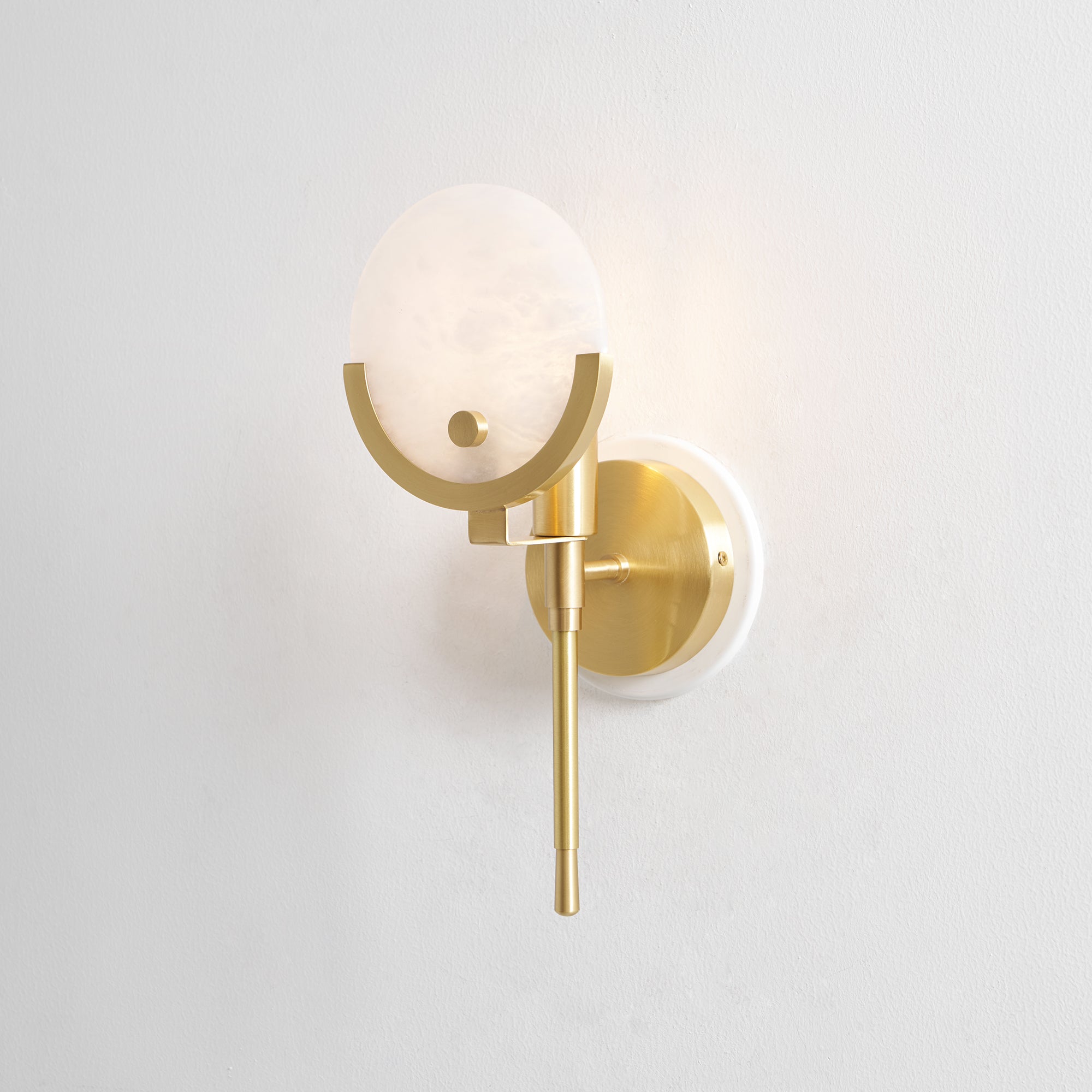 Clérachic studio view of the compact Zavarara sconce unlit, shade angled to show its stone face and brass frame.