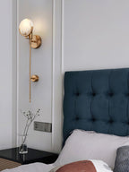 Clérachic zavarara sconce mounted beside a blue tufted headboard, its veined alabaster shade warmly lit.