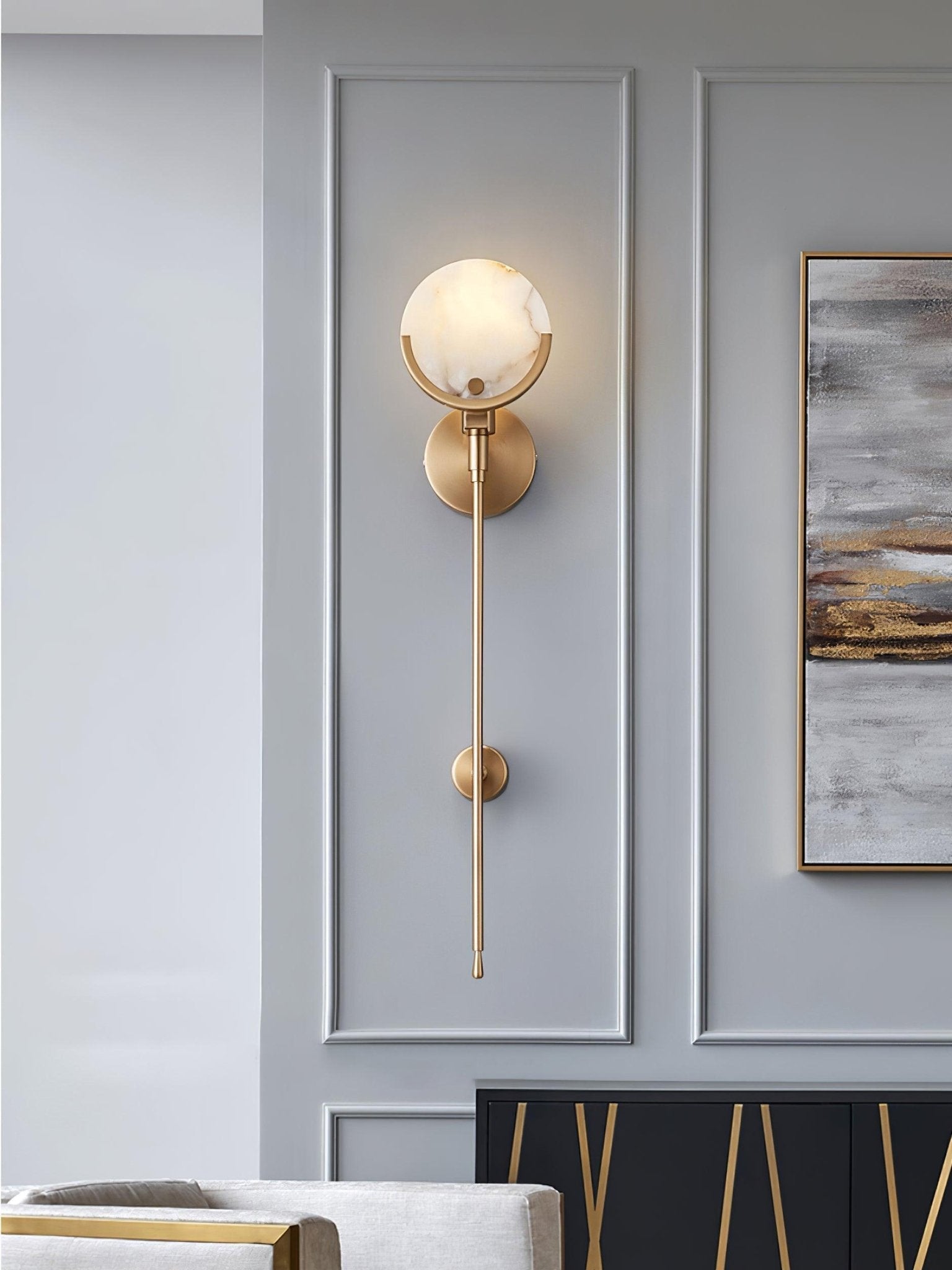 Clérachic zavarara sconce lit on a grey panelled wall, the alabaster shade showing warm amber veining.
