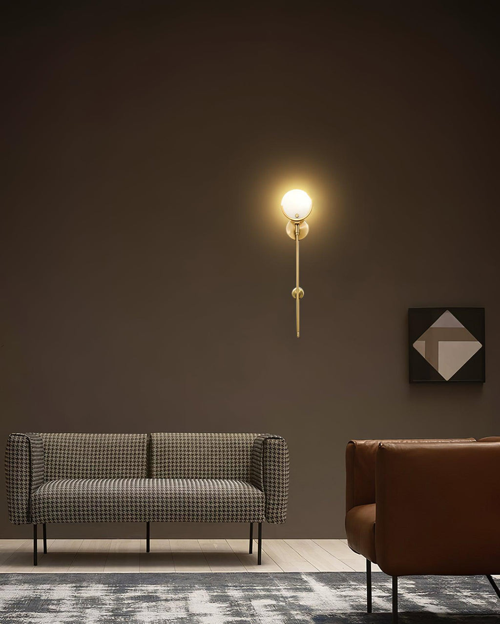Clérachic zavarara wall light lit against a dark brown wall above a houndstooth sofa, throwing a soft pool of light.