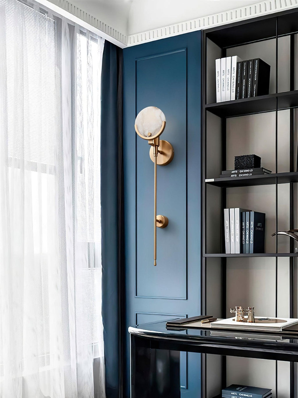 Clérachic zavarara wall light unlit on a deep blue panelled wall in a study, beside a black bookshelf.