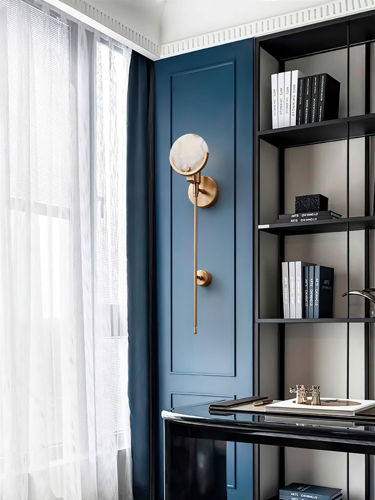 Clérachic zavarara wall light unlit on a deep blue panelled wall in a study, beside a black bookshelf.